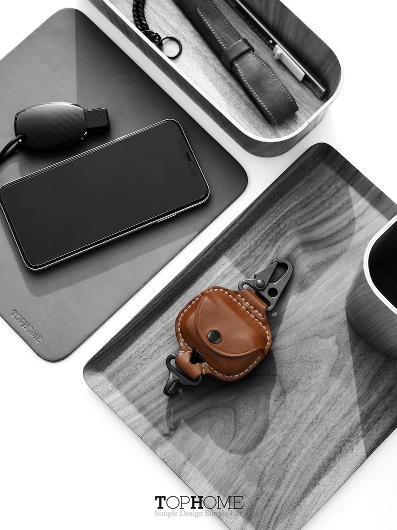 Op de afbeelding: Een set van drie grijze houten trays met een zwarte telefoon, een zwarte fluit, een bruine leren sleutelhanger met een metalen karabijnhaak en een zwart-wit logo met de tekst "TOPHOME Simple Design Simple Life".