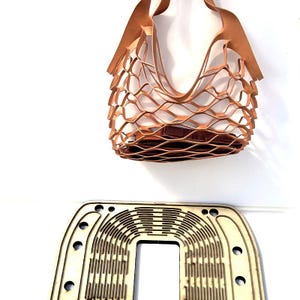 May include: A light brown leather tote bag with a unique woven design. The bag has a rectangular shape and a brown interior. Below the bag is a wooden craft template with a similar woven pattern.