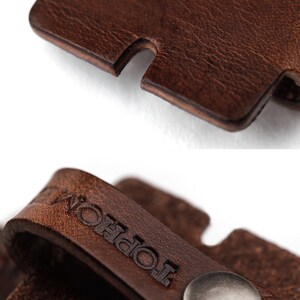 May include: A brown leather strap with a silver metal button and the word "Topol" embossed on it.