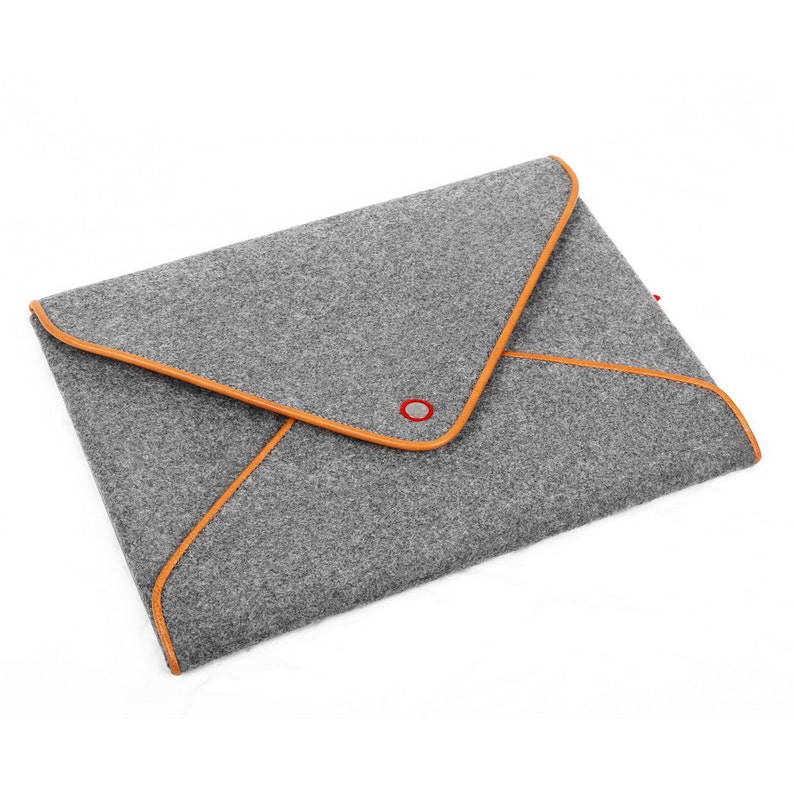 May include: Grey felt laptop sleeve with orange trim and a red button closure. The envelope-style case has a triangular flap and is designed to protect a laptop or tablet. The minimalist design is suitable for everyday use.