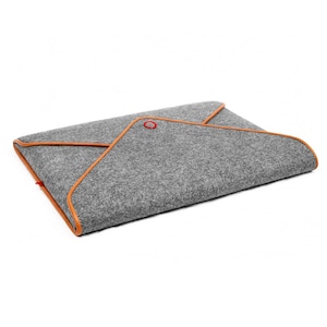 May include: Grey felt laptop sleeve with orange trim and a red accent. The sleeve has an envelope-style design. The orange trim outlines the edges, adding colour. A red accent is visible on the top corner. The sleeve is designed to hold a laptop.