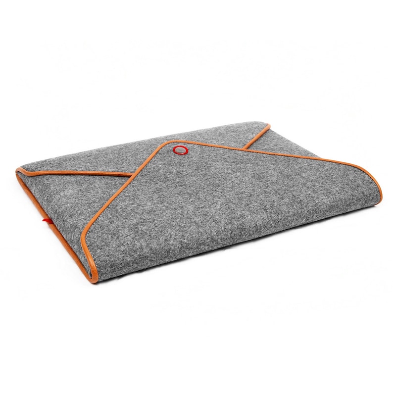 May include: Grey felt laptop sleeve with orange trim and a red accent. The sleeve has an envelope-style design. The orange trim outlines the edges, adding colour. A red accent is visible on the top corner. The sleeve is designed to hold a laptop.