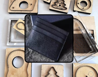 May include: A black leather card holder with three visible slots, centered over a collection of various wooden and metal cutting dies used for leather crafting, including shapes like trees, circles, and rectangular frames with metal blades.