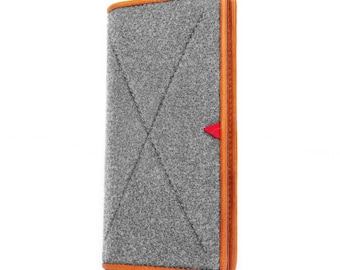 May include: A gray felt wallet with a brown leather trim and a red accent. The wallet has a stitched pattern and is closed.