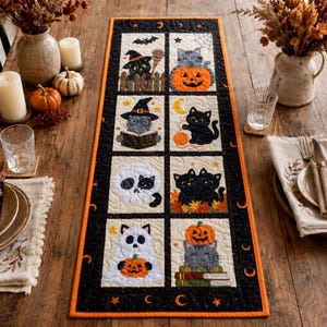 May include: A rectangular quilted table runner featuring eight distinct panels with Halloween-themed illustrations of black cats, pumpkins, skulls, and ghosts. The runner has a black border with orange crescent moons and stars on a wooden table.