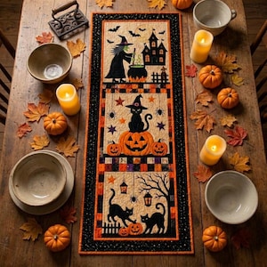 May include: A rectangular Halloween-themed table runner featuring three vertical panels with appliqued designs of a witch with a cauldron, a black cat on a pumpkin, and two black cats near lanterns, all bordered by a black and orange checkered pattern.