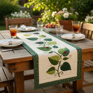 Puede incluir: Un camino de mesa rectangular con un centro de color crema de textura acolchada y un patrón de enredadera verde aplicado con pequeñas mariquitas rojas. El camino tiene un borde verde oscuro con un pequeño estampado floral blanco.