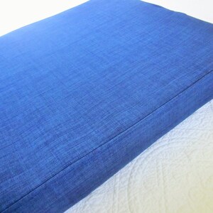 May include: A blue rectangular cushion with a textured fabric surface.
