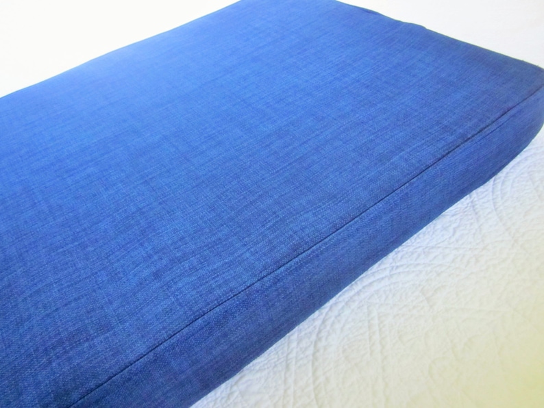 May include: A blue rectangular cushion with a textured fabric surface.
