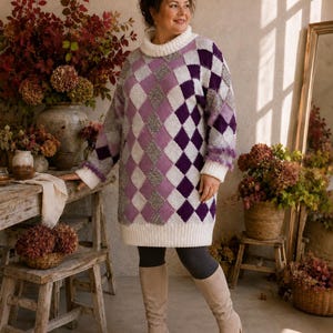May include: A long-sleeved jumper dress featuring a white roll-neck, cuffs, and hem, decorated with a purple, lavender, and grey argyle diamond pattern. The knit garment has a textured finish and reaches above the knees, paired with dark leggings.