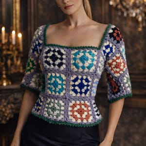 Könnte beinhalten: Gehäkeltes Oberteil mit quadratischem Ausschnitt und kurzen Ärmeln. Das Oberteil besteht aus bunten Granny Squares in Blau, Grün, Orange und Weiß auf einem lavendelfarbenen Hintergrund. Die Kanten sind mit grünem Garn eingefasst. Dazu ein schwarzer Rock.