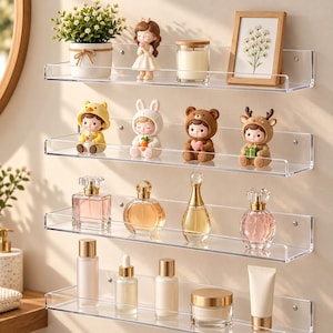 May include: Four clear acrylic wall-mounted shelves holding various items. The top shelf features a potted plant, a girl figurine, a candle, and a framed floral print. The second shelf displays four animal-themed character figurines. The third shelf holds four glass perfume bottles. The bottom shelf contains various skincare bottles and a jar.