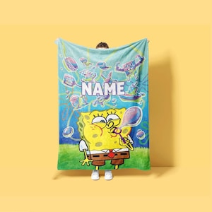 May include: A rectangular fleece blanket featuring a vibrant SpongeBob SquarePants graphic. The design includes the character blowing bubbles, various underwater icons, and the word NAME in bold white capital letters against a blue background.