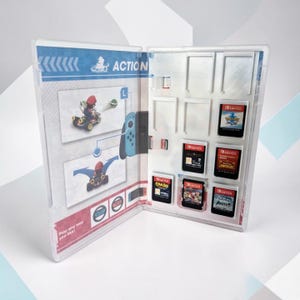 May include: A clear plastic Nintendo Switch game storage case open to reveal internal slots holding five game cartridges. The left interior panel features printed graphics of Mario in a kart and the text ACTION and Play any way you like.