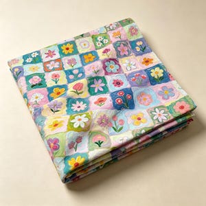 May include: A folded fabric textile featuring a grid pattern of squares, each containing a unique hand-painted style flower illustration. The color palette includes shades of blue, green, pink, yellow, and white, with visible brushstroke textures.