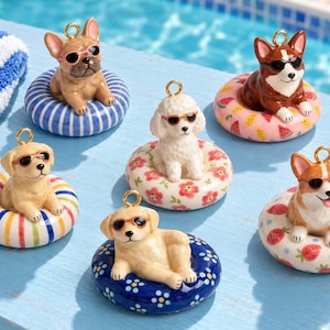 May include: Six ceramic dog figurines, each wearing sunglasses and resting inside a colourful patterned pool float. The dogs include a French Bulldog, a Poodle, and Corgis, all featuring a gold-toned metal loop at the top for hanging as ornaments.