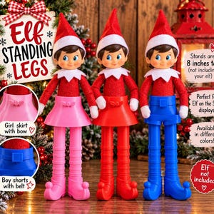 May include: Three elf dolls wearing red hats and jackets with white collars. Each elf stands on a plastic base with legs: one pink skirt with a bow, one red skirt, and one blue pair of shorts with a belt. Text reads: Elf Standing Legs, 8 inches tall.