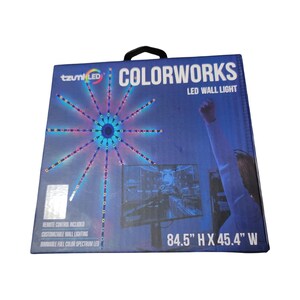 May include: A Tzumi LED Colorworks LED wall light in a blue box. The packaging features a starburst light graphic, a person with a raised arm, and a monitor. Text includes "COLORWORKS," "LED WALL LIGHT," and "84.5" H X 45.4" W" with remote control.