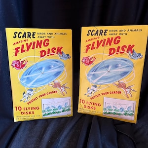 May include: Two yellow and red packages of 10 flying disks to scare birds and animals away from your garden. The packages feature a cartoon illustration of a flying disk, a bird, and a rabbit. The text on the package reads "SCARE BIRDS AND ANIMALS AWAY WITH AMAZING FLYING DISK".