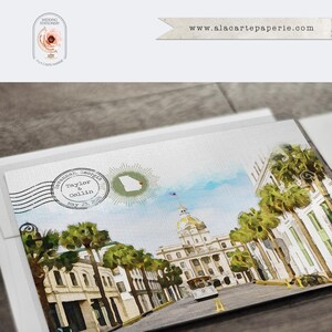 May include: A rectangular wedding invitation card featuring a watercolor illustration of a Savannah, Georgia street scene with palm trees, a domed building, and a trolley. A postmark stamp displays the text Taylor & Collin May 23, 2026.