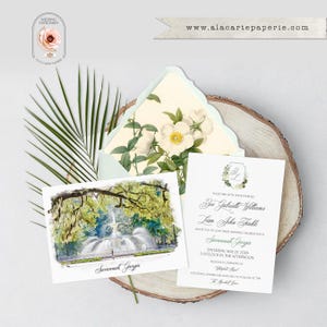 May include: A wedding invitation set featuring a watercolor illustration of a fountain in Savannah, Georgia, a floral-lined envelope, and a white card with black text detailing the ceremony for Zoe Gabrielle Williams and Liam John Finkle.
