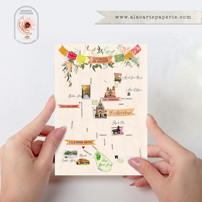 Puede incluir: Un mapa de San Miguel de Allende, M&eacute;xico, con ilustraciones en acuarela de lugares emblem&aacute;ticos y el texto "San Miguel de Allende". El mapa est&aacute; sostenido por dos manos. La direcci&oacute;n del sitio web www.alacartepaperie.com est&aacute; en la parte superior.