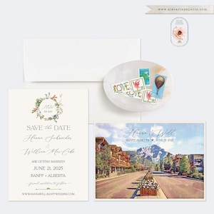 May include: Wedding stationery set featuring a Save the Date card, invitation, and a scenic postcard of Banff, Alberta. Includes a white envelope and decorative stamps on a small oval dish. The Save the Date card has floral accents.