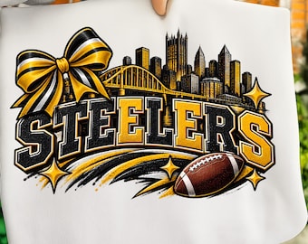 Puede incluir: Un artículo de tela blanca con un estampado gráfico de la palabra STEELERS en letras negras y amarillas. El diseño incluye un lazo grande negro y amarillo, un puente amarillo, un horizonte de ciudad y un balón de fútbol americano marrón.
