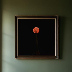 May include: A square framed wall art piece featuring a dark night sky with a large, vibrant orange full moon positioned directly behind the pointed spire of a church steeple, which is topped with a small cross silhouette against the darkness.