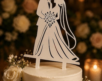 May include: A white cake topper featuring a silhouette of a couple standing together. The figure on the left wears a suit, and the figure on the right wears a dress with a veil and holds a bouquet of flowers. The topper has two prongs at the base.