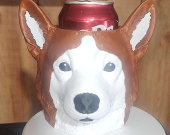 May include: A brown and white dog-shaped beverage cooler featuring a sculpted head with large upright ears and a black nose. The container is designed to hold a standard aluminum soda can, which is partially visible inside the top opening.