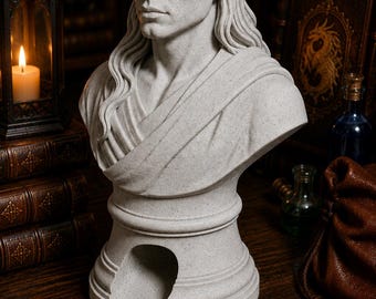May include: A light gray speckled stone-effect bust of an elf with long hair and pointed ears. The sculpture features a draped garment across the chest and a hollow, arched opening at the base, designed as a functional holder or display piece.