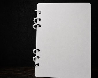 May include: A white A5 notebook cover featuring a 6-ring binder mechanism with printed rings. The text A5 NOTEBOOK COVER - 6 RING BINDER WITH PRINTED RINGS is displayed at the top, and 3MF | INSTANT DOWNLOAD is printed at the bottom.