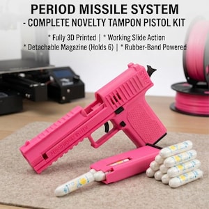 May include: A bright pink 3D printed novelty tampon pistol kit labeled PERIOD MISSILE SYSTEM. The set includes a pistol with a working slide action, a detachable magazine, and a small pile of white tampons. It is rubber-band powered.