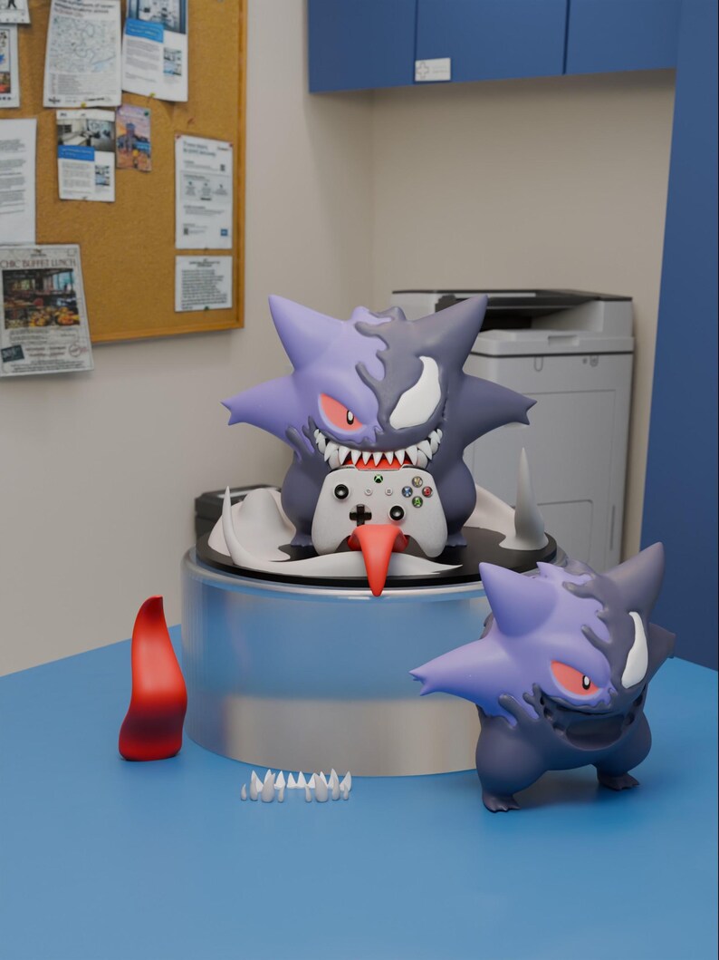 May include: A purple and dark grey Gengar-inspired figure with a split face design, sharp teeth, and red eyes, holding a white Xbox controller with a long red tongue. A smaller matching figure stands nearby with a separate red tongue and teeth.