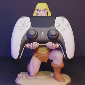 Pode incluir: Uma estatueta de um personagem loiro de pele bronzeada, vestindo uma tanga e botas castanhas, ajoelhado numa base circular enquanto segura com ambas as mãos um comando de videojogos preto e branco com um logótipo central da PlayStation.