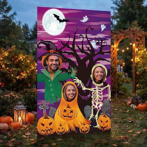 May include: A rectangular Halloween photo cutout board featuring a purple night sky with a full moon, a black tree silhouette, and ghosts. The board has three face holes depicting a scarecrow, a pumpkin character, and a skeleton figure.