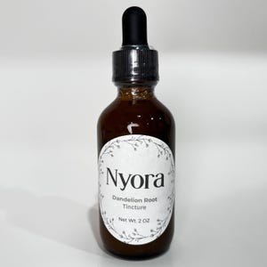 May include: A brown glass dropper bottle with a black cap containing Nyora Dandelion Root Tincture. The white oval label features a delicate floral border and the text: Nyora, Dandelion Root, Tincture, Net Wt. 2 OZ. The bottle is upright.