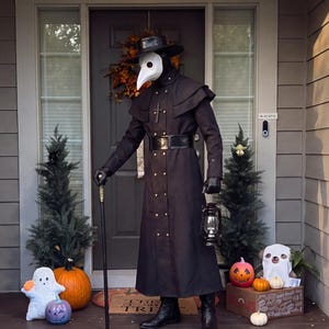 May include: A plague doctor costume featuring a long black coat with gold buttons, a wide-brimmed black hat, a white bird-like mask, black gloves, and black boots. The outfit includes a cross pendant, a black cane, and a handheld black lantern.