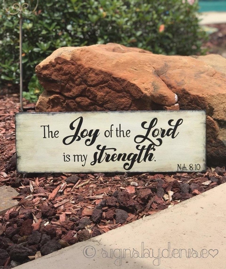 May include: A white wooden sign with black lettering that reads "The Joy of the Lord is my strength.  Neh. 8:10".