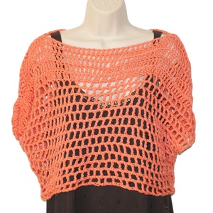 May include: A coral crochet top with a loose, open-weave design. The top has short sleeves and a wide neckline.