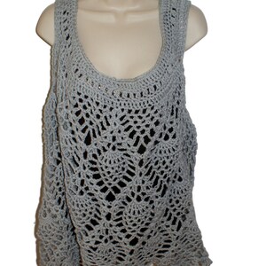 May include: A gray crochet tank top with a delicate, lacy pattern. The top has a scoop neck and a loose, flowy fit.