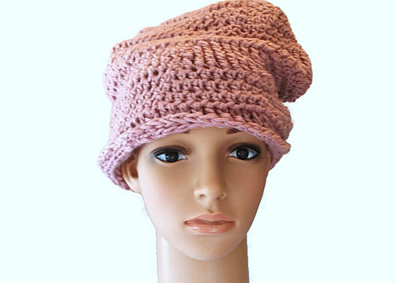May include: A pink crocheted beanie with a slouchy design. The beanie is made with a soft yarn and has a simple, elegant style.