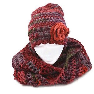 May include: A crocheted hat and scarf set in shades of red, purple, and green. The hat has a crocheted flower embellishment.