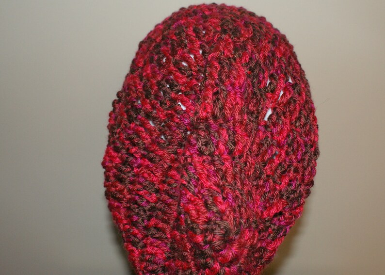 May include: A red and brown knitted hat with a textured pattern.
