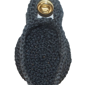 Puede incluir: Un macetero colgante de ganchillo gris oscuro con un anillo de metal dorado en la parte superior.