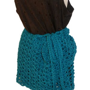May include: Teal crochet wrap skirt with a delicate openwork pattern. The skirt is tied at the waist and falls to the mid-thigh.