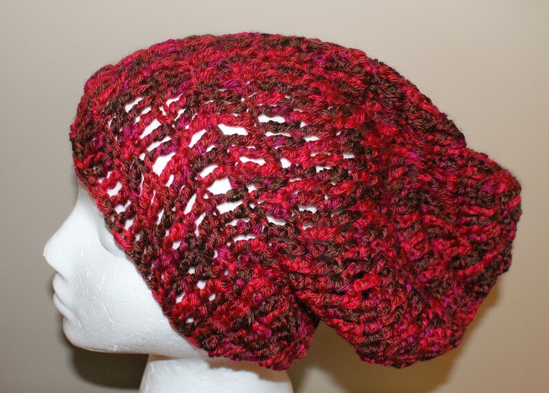 May include: A red and brown crocheted beanie hat with a loose, slouchy fit.