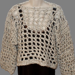 May include: A beige crocheted sweater with a loose, open-weave design. The sweater has long sleeves and a wide, round neckline.
