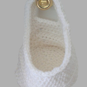 May include: A white crocheted hanging basket with a gold metal hook.
